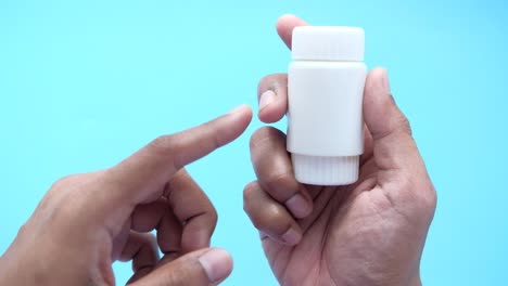 hand holding a white medicine bottle