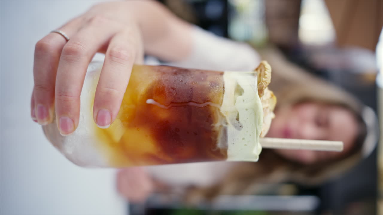 Close view of a woman holding a cold brew espresso shot drink with matcha foam and straw in a cafe