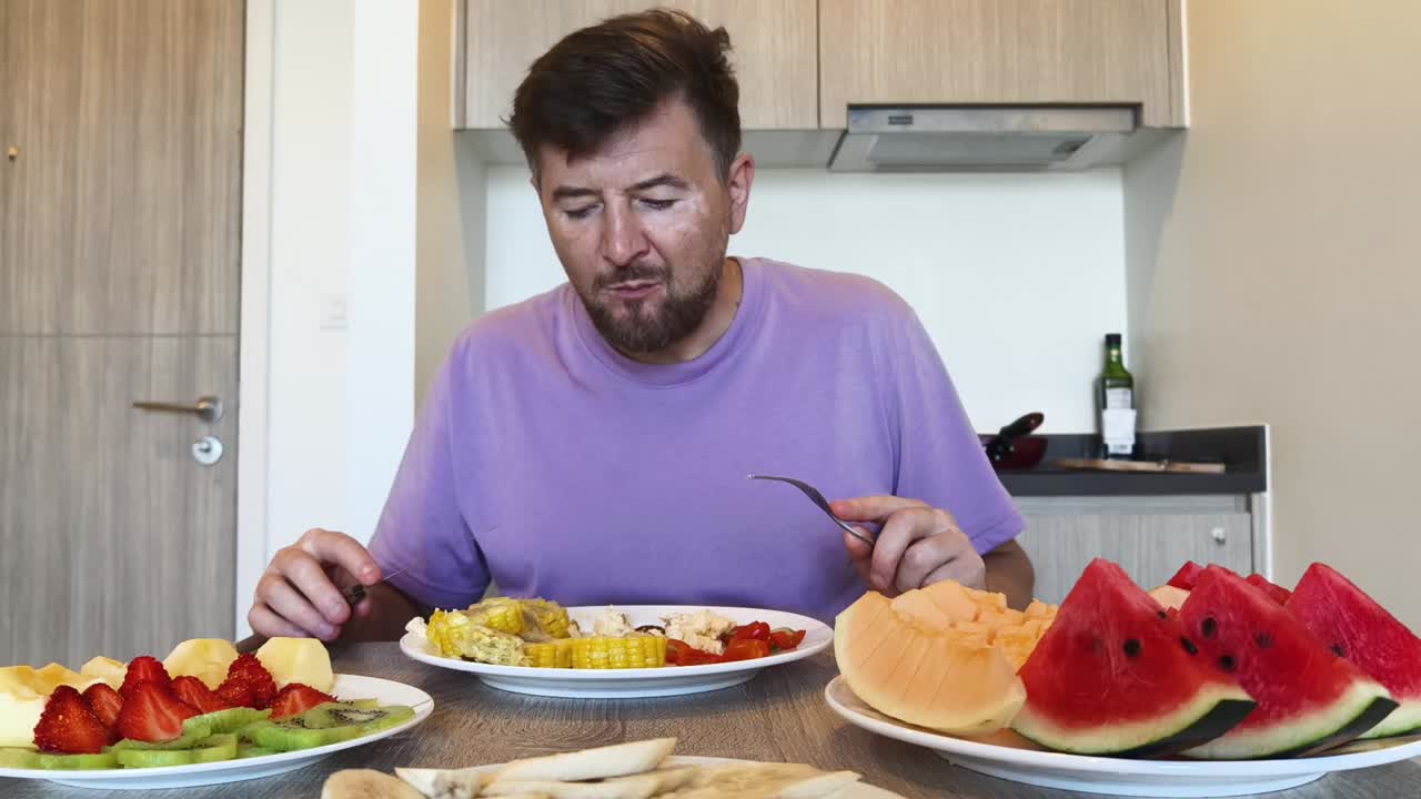 Man eating a plate of fruit and corn