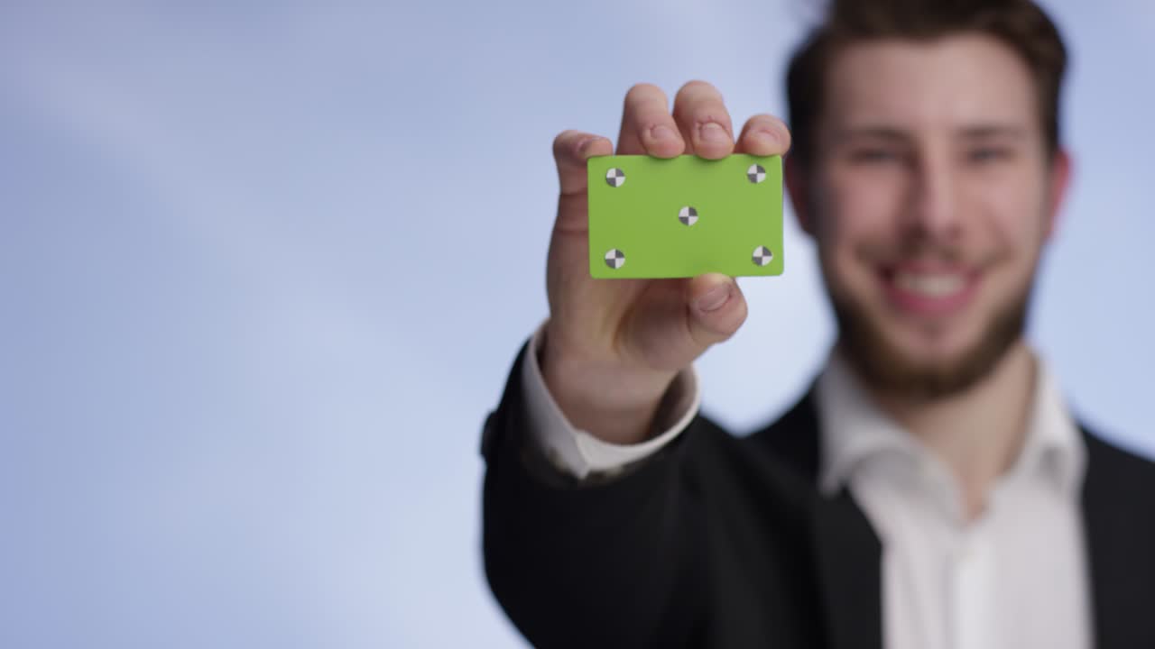 Young and handsome man smiling and presenting a buisness card into the camera