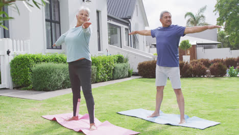 happy senior diverse couple practicing yoga in garden