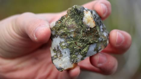 un hombre muestra una roca llena de piedras preciosas