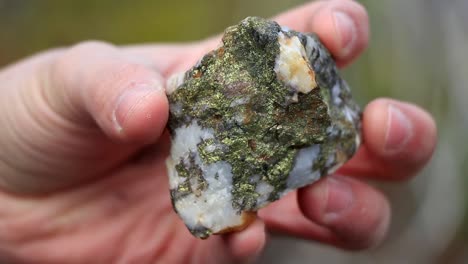 a man is showing a rock full a gemstone