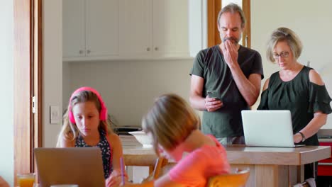 parents using laptop and mobile phone while kids studying in kitchen 4k