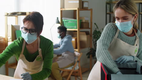 female coworkers in masks packing eco food orders in delivery bag