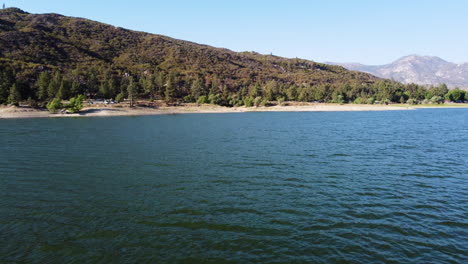 Lake-Hemet-and-majestic-mountain-range-in-low-angle-flying-over-water