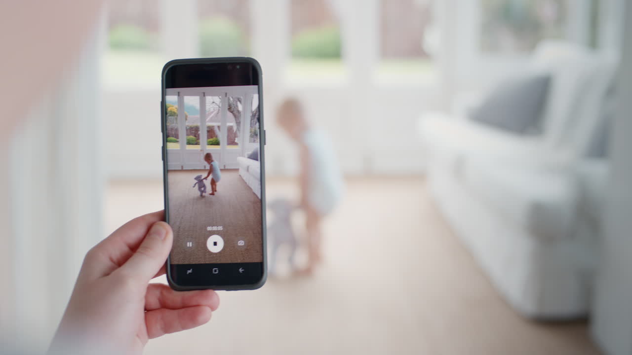 madre tomando video del bebé usando un teléfono inteligente disfrutando de fotografiar a un bebé feliz con una cámara de teléfono móvil compartiendo el estilo de vida de la maternidad en las redes sociales imágenes de 4k