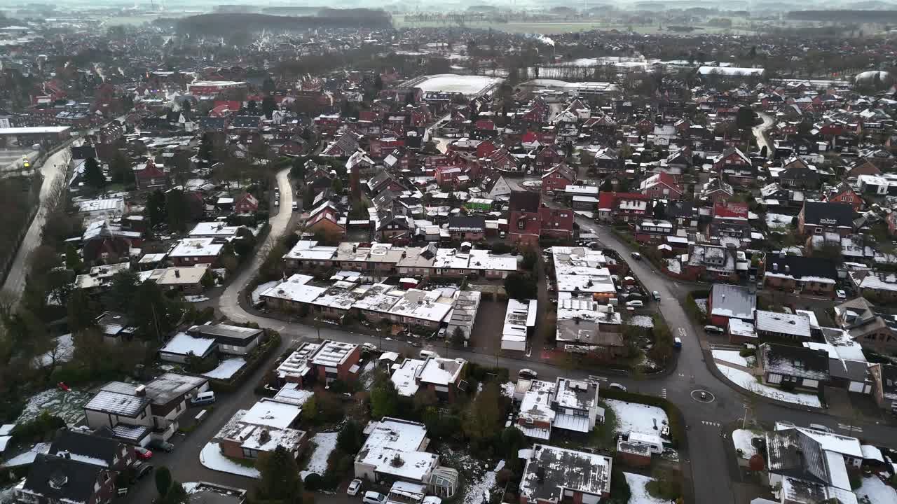 Small snowy American town during frosty and icy winter day. American neighborhood with snow-covered roofs. Aerial top down flyover shot.