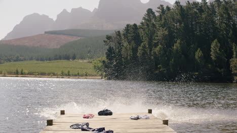 friends undressing jumping off jetty in lake at sunset having fun splashing in water enjoying freedom sharing summer vacation adventure