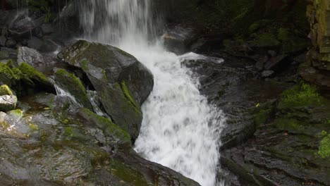 Mid-shot-of-the-waterfall-landing-onto-rocks-and-flowing-away-at-Lumsdale-waterfalls,-Matlock