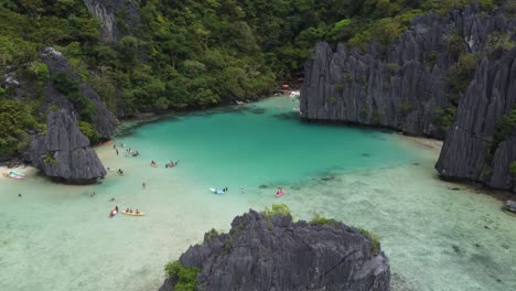 aerial jib shot of cadlao lagoon or ubugon cove in el nido, philippines with people kayaking and swimming in tropical turquoise water