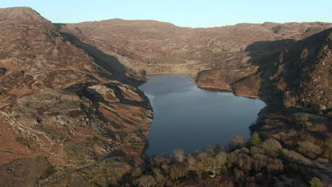 una vista aérea del lago liyn cwm bychan cuando el sol comienza a ponerse, volando de derecha a izquierda alrededor del final del lago, gwynedd, norte de gales, reino unido