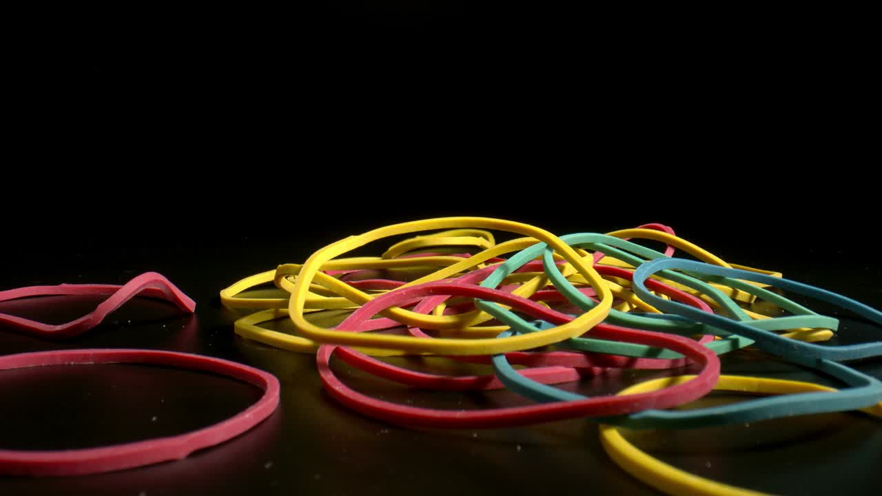 Falling lacky bands for money on black background. Falling rubber bands on a black background as a symbol of cashless payments. Zoom in.