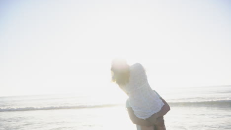 Biracial-couple-enjoys-a-playful-moment-on-a-sunlit-beach-with-copy-space