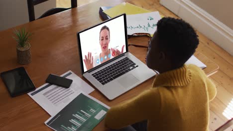 mujer afroamericana que usa una computadora portátil en una videollamada con una colega que trabaja desde casa