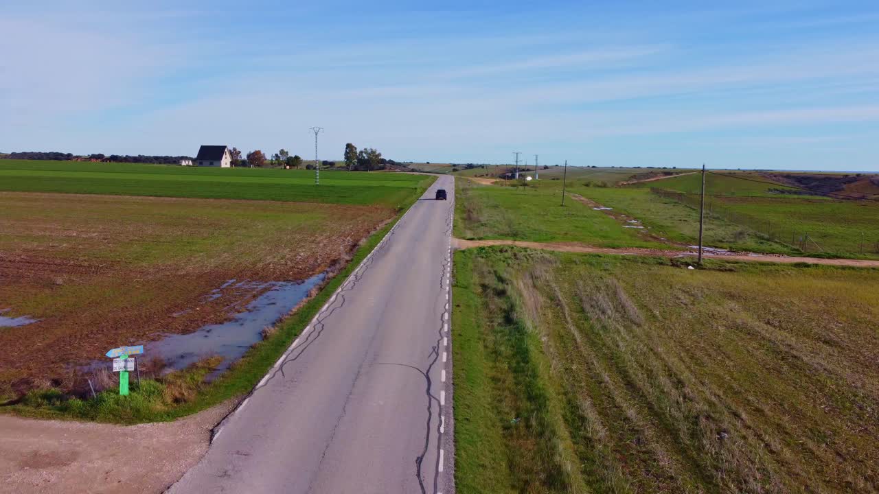 검은색 자동차는 푸른 잔디 푸른 하늘로 둘러싸인 전통적인 멋진 마을로 환상적인 길을 운전합니다