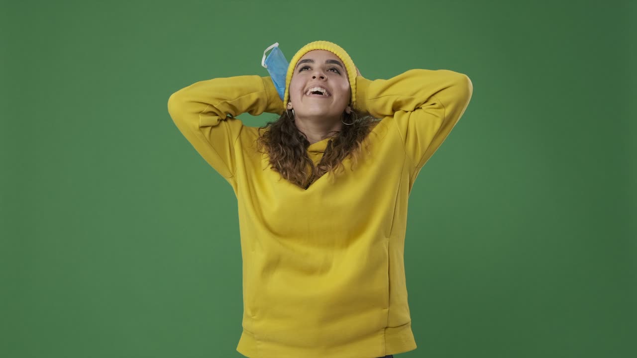 Frau atmet frische Luft ein, während sie die Schutzmaske vor einem Greenscreen abnimmt