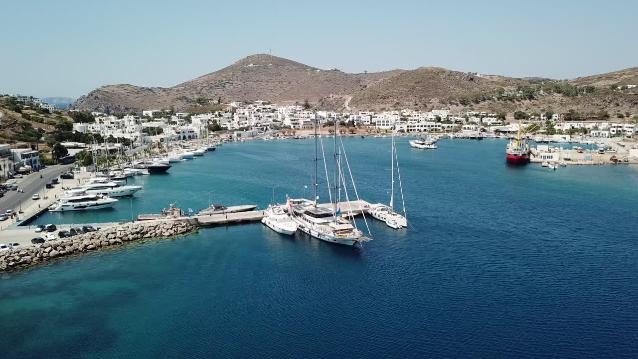 Grecia, Isola di Patmos, riprese con drone del porto dell'isola con barche a vela, yacht e imbarcazioni ormeggiate. Isola pittoresca con splendidi paesaggi, edifici e barche