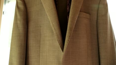 Grooms-tan-suit-and-purple-tie-hanging-in-the-window-before-he-gets-ready-for-a-wedding