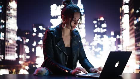 a focused woman in a leather jacket sits at a desk, typing on a laptop against a mesmerizing backdrop of urban skyscrapers and bright city lights at night