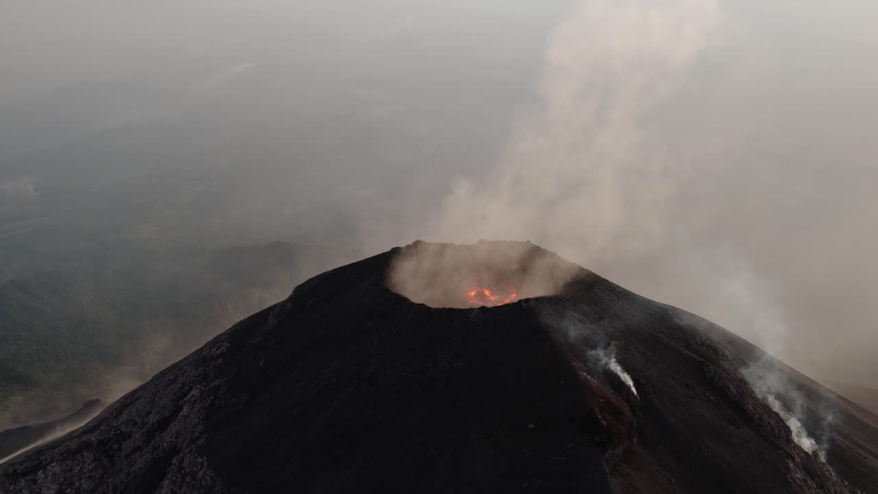 Orbiting aerial view of the glowing crater of Fuego Volcano in Guatemala with visible lava inside the summit