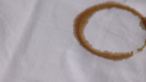 una camisa blanca de algodón manchada con manchas de café marrón. debe lavarse bien en la lavadora