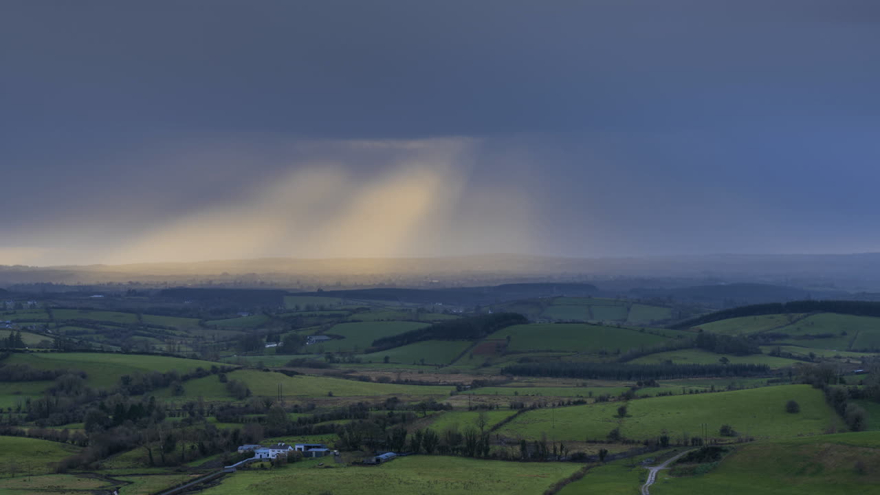 아일랜드 카운티 슬라이고에 있는 케시 동굴에서 극적인 흐린 일몰 동안 잔디밭과 언덕의 시골 농업 풍경의 시간 경과