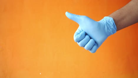 hand in blue glove giving a thumbs up