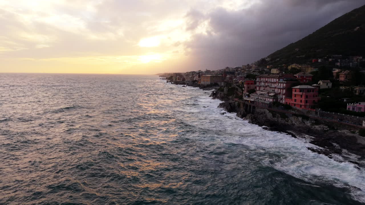 Drone aereo sorvola il mare mosso del Mediterraneo che si infrange sulla costa di Genova al tramonto