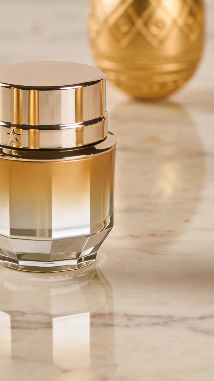 Faceted glass cosmetic jar sitting centered on shiny marble table, reflecting decorative gold eggs