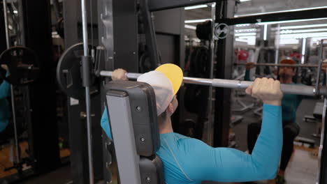 hombre haciendo presión de hombro con barra sentado en la máquina de smith