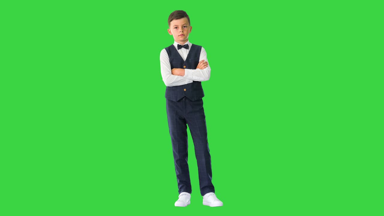 푸른 스크린, 크로마 키에서 카메라를 보면서 팔을 고 주머니에 손을 넣는 자신감 넘치는 젊은 소년