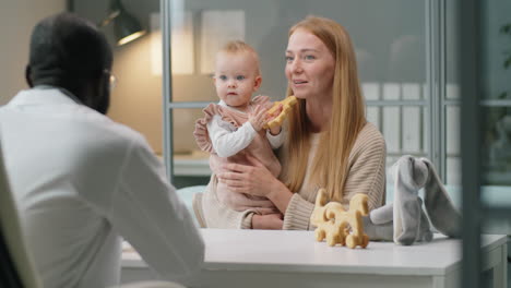 mother holding baby and speaking with pediatrician in clinic