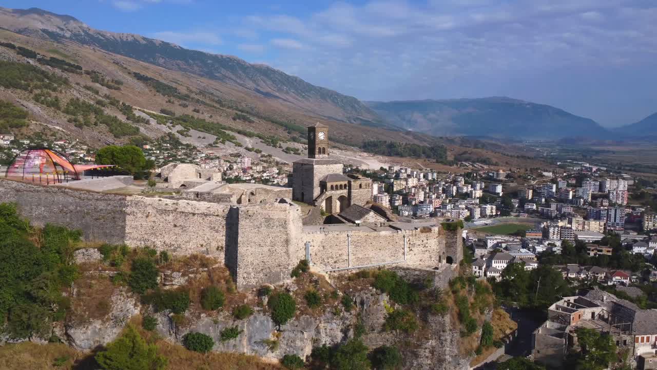 Vista aerea di un castello con torre dell'orologio e sfondo montano