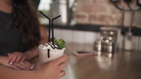 Vista-Más-Cercana-De-Un-Cóctel-Traído-Por-El-Camarero-Para-La-Joven-Pareja-Sentada-En-La-Mesa-De-Madera-Con-Un-Trago-De-Café