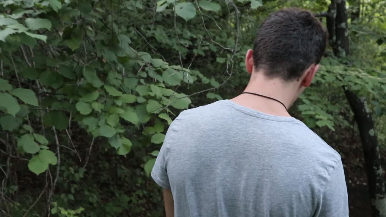 녹색 숲에서 걷는 남자 - 뒤에서 총