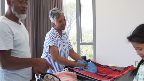 Biracial-couple-in-casual-clothing-sorts-laundry-with-their-young-daughter-in-a-bright-room