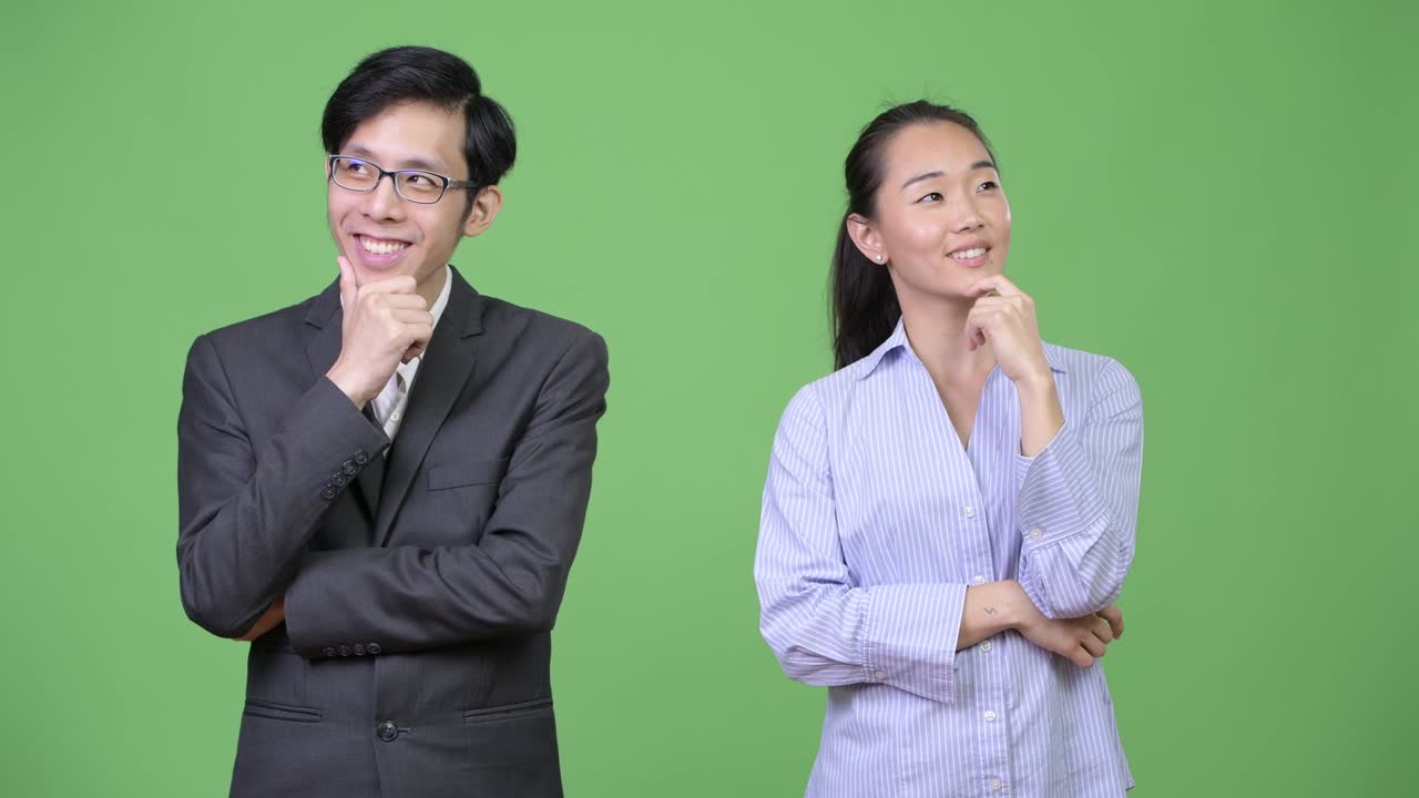 Young happy Asian business couple thinking together