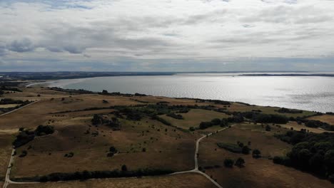 Vista-Aérea-De-La-Costa-De-Sejerøbugten-Con-Colinas,-Campos-Y-Océano