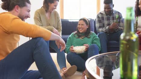 Felices-Y-Diversos-Amigos,-Hombres-Y-Mujeres,-Relajándose-En-Casa-Juntos-Bebiendo-Cervezas-Y-Comiendo-Palomitas-De-Maíz.