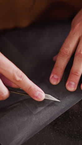 worker sharpens small cutter with sandpaper on table in workshop close upper view. master prepares instrument in studio. knife for leather cutting