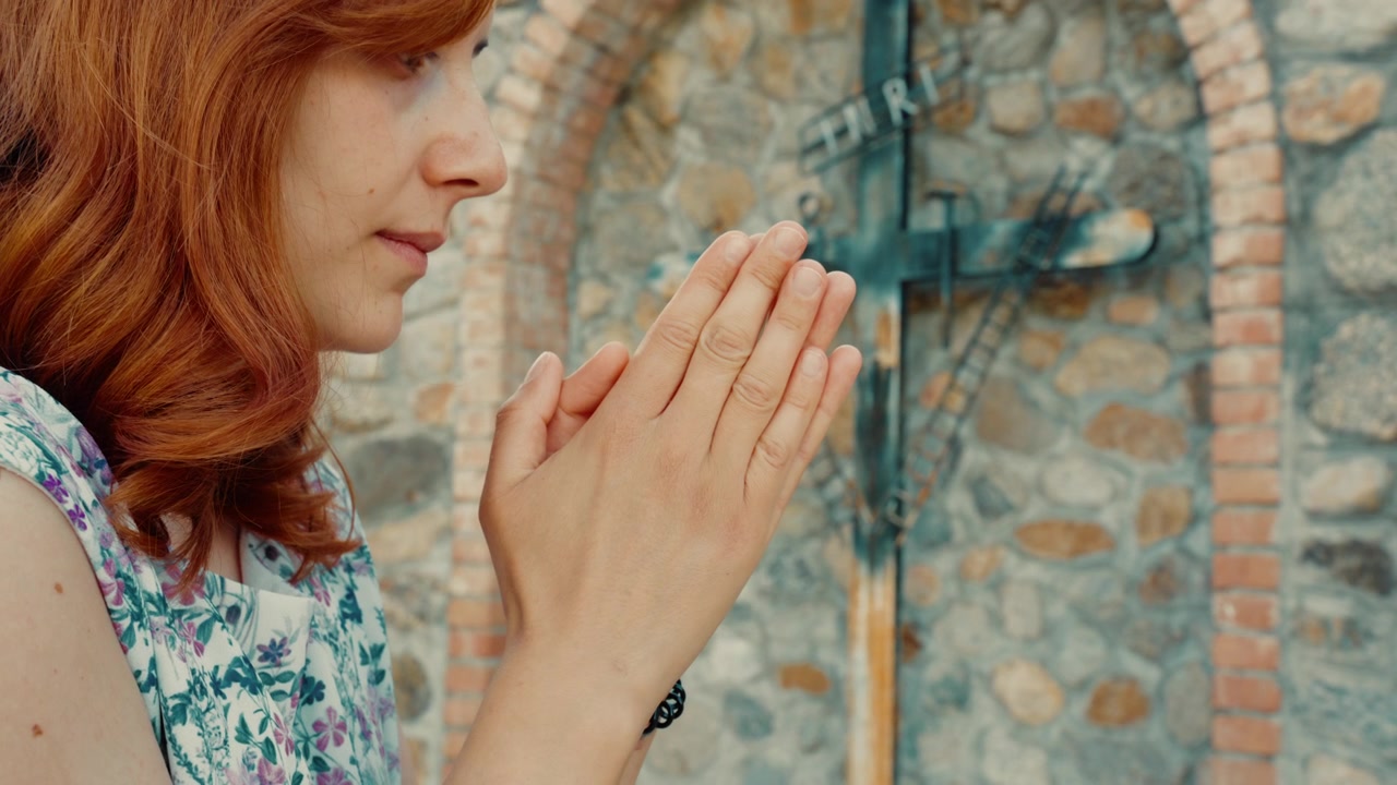 Donna prega per Gesù e i malati con le mani giunte vicino a un crocifisso cristiano