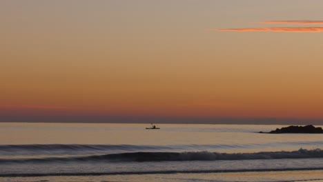 Hombre-Rema-Kayak-En-Mar-Tranquilo-Al-Amanecer,-Silueta,-Costa-Mediterránea-De-España