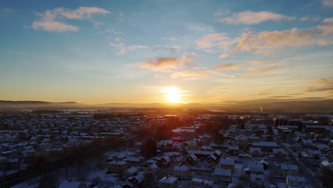 sunset over snow-covered swedish town, with a warm glow across rooftops