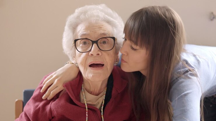 Granddaughter embracing and kissing her grandmother in a geriatric