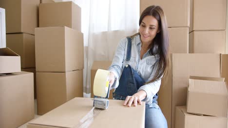 mujer joven mudándose a casa empacando cajas