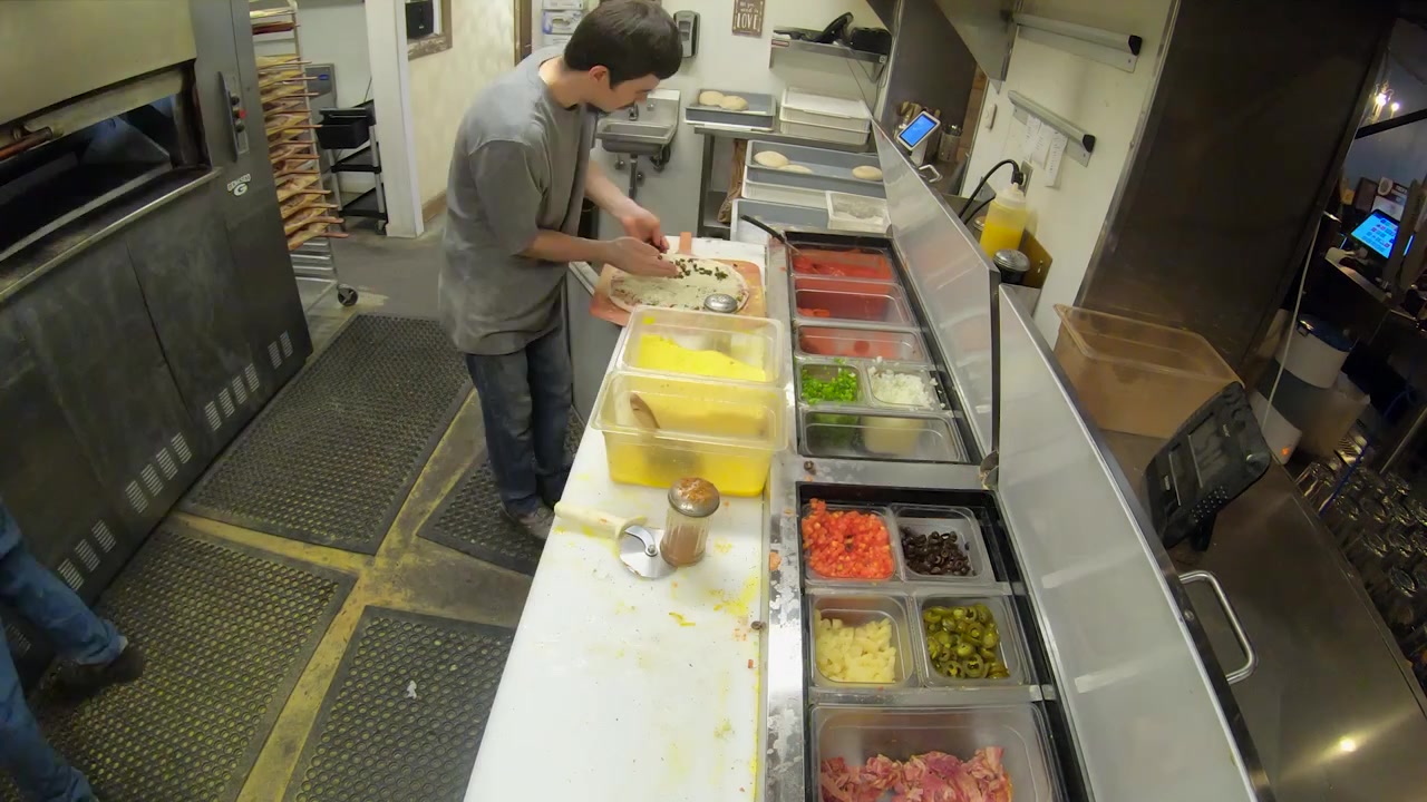Time-lapse di due uomini che preparano pizze nella cucina di una pizzeria-ristorante a conduzione familiare.