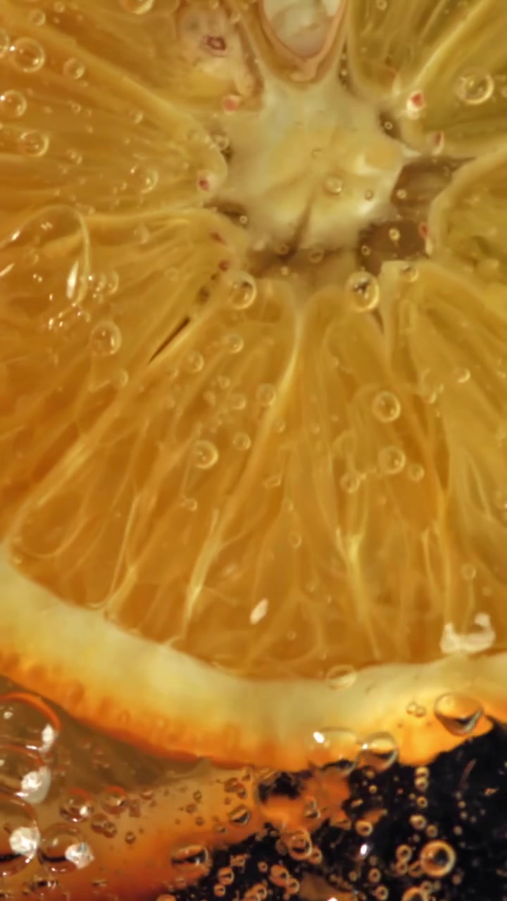 Fetta d'arancia rinfrescante immersa in acqua frizzante con schizzi
