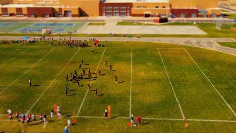 Miniature-tilt-shift-effect-of-a-youth-football-game-at-a-school-in-suburban-America