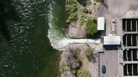 an aerial view of the discharge channel shows clean water being released from the plant into the river, with visible ripples and foam patterns where the flows meet